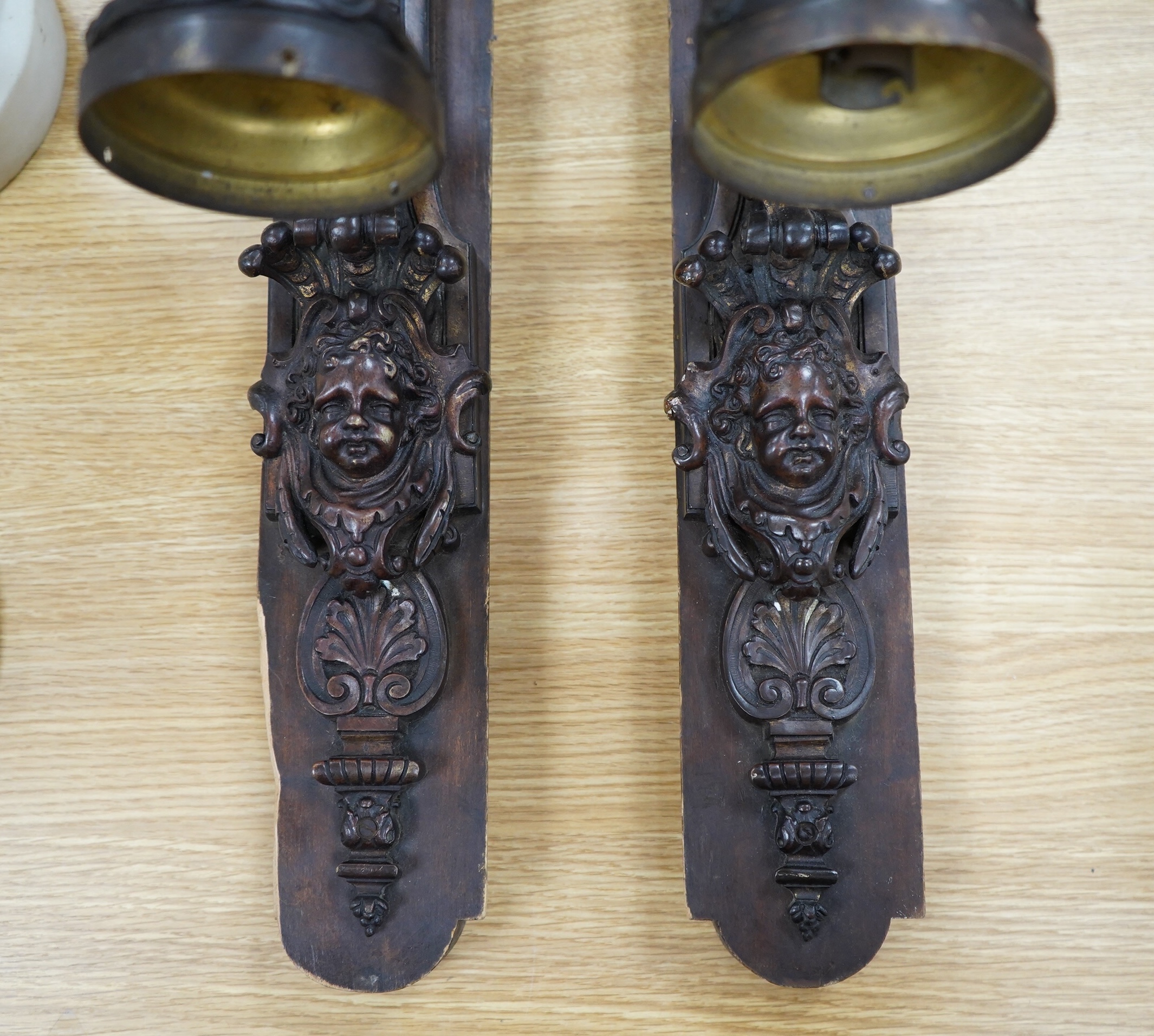 A pair of French bronze wall lights, c.1900 decorated with masks, mounted on wooden plinths, 54cm high. Condition - poor to fair